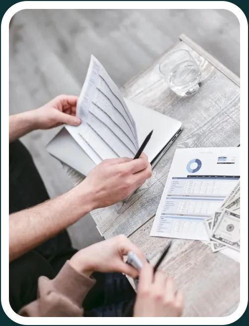 Hands reviewing printed invoices and payment reports at a desk